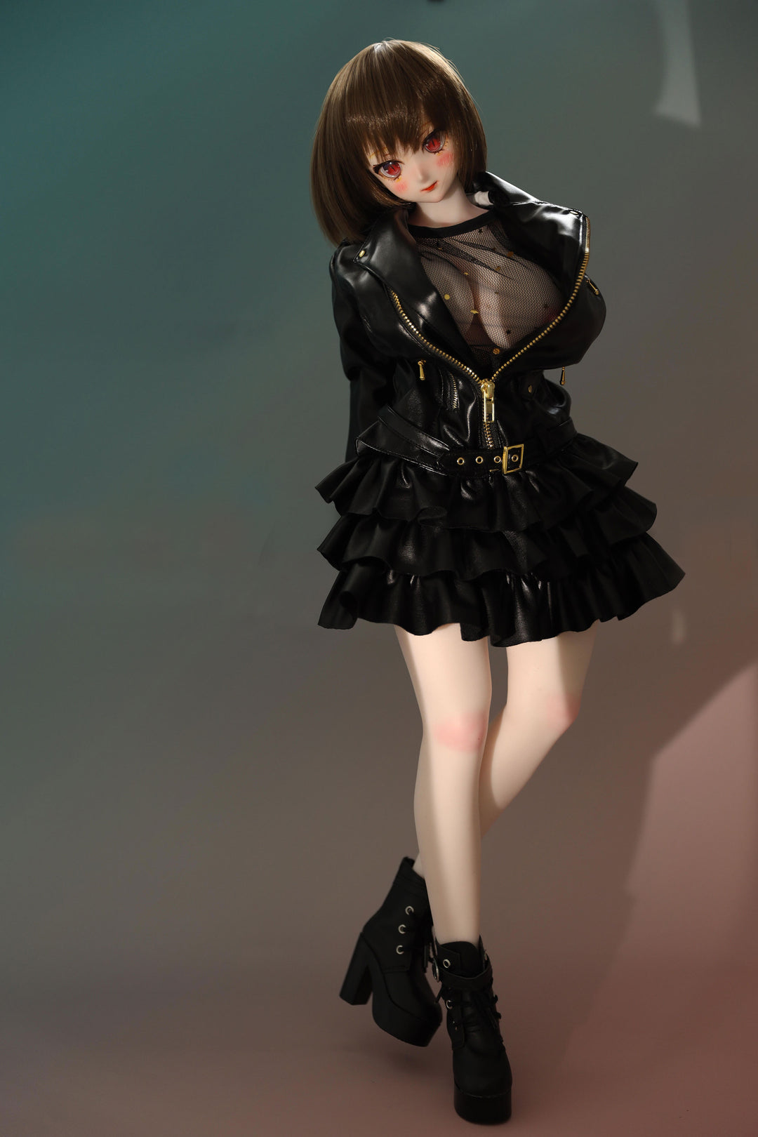 CLIMAX DOLL Mini J60cm P Hybrid - Zella (White) - Full-body standing pose in a glossy black ruffled jacket over a sheer black top, with black boots, short brown bob, teal-green backdrop.