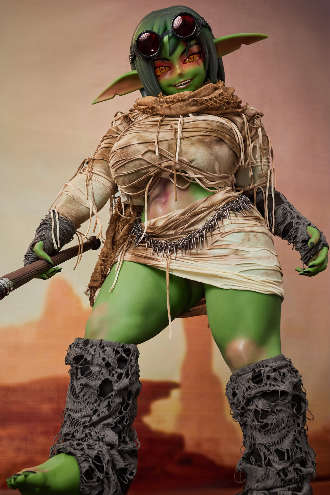CLIMAX DOLL ULW SiF120 cm Silicone - Barza (Green) full body rear view in tattered tan wrap with staff, short green hair, desert red background
