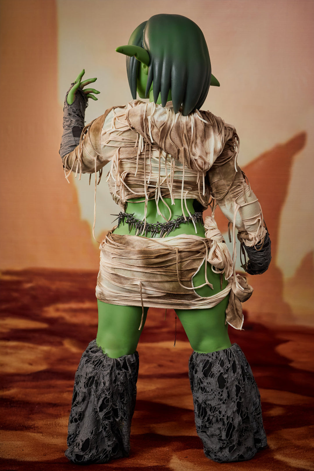 CLIMAX DOLL ULW SiF120 cm Silicone - Barza (Green) close-up upper body front view in tan wrap, short green hair, desert red background
