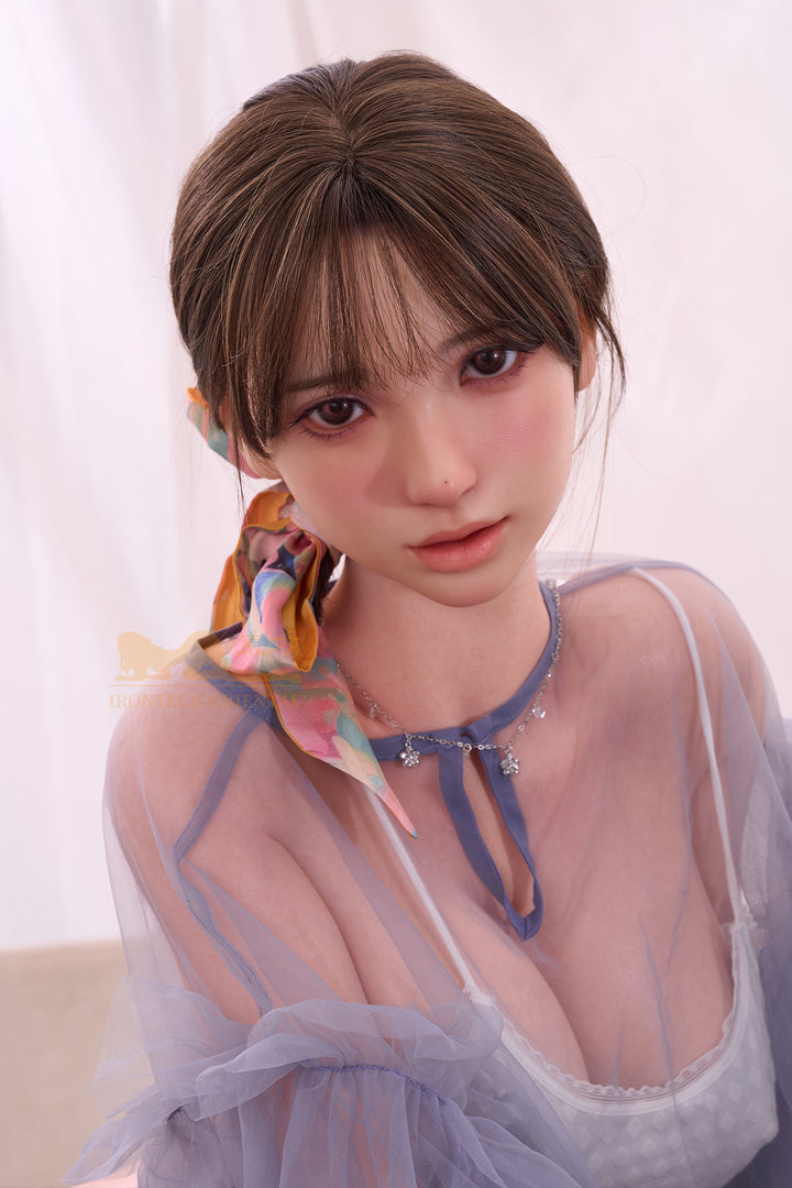 Irontech Doll 161T Evie silicone sex doll with long brown hair, green lingerie, and purple robe, posing softly against a floral background.