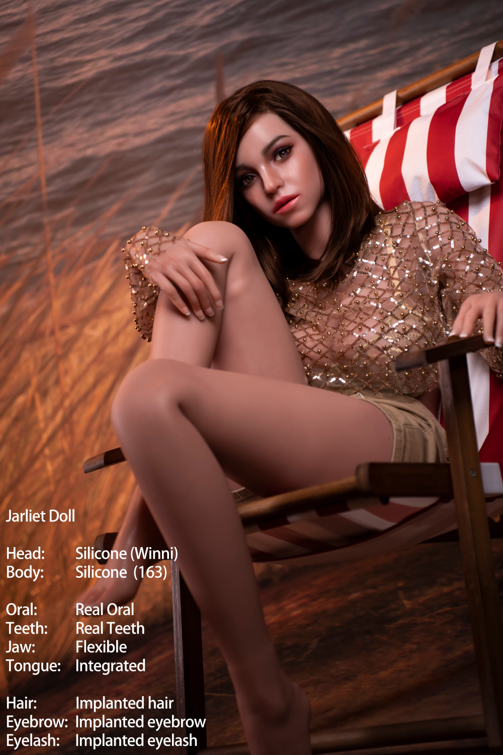 Jarliet Doll 163 cm D Silicone - Winni sitting in a red and white striped beach chair. She has medium-length brown hair and is wearing a gold sequined mesh top and tan shorts. The background features a sunset beach scene.