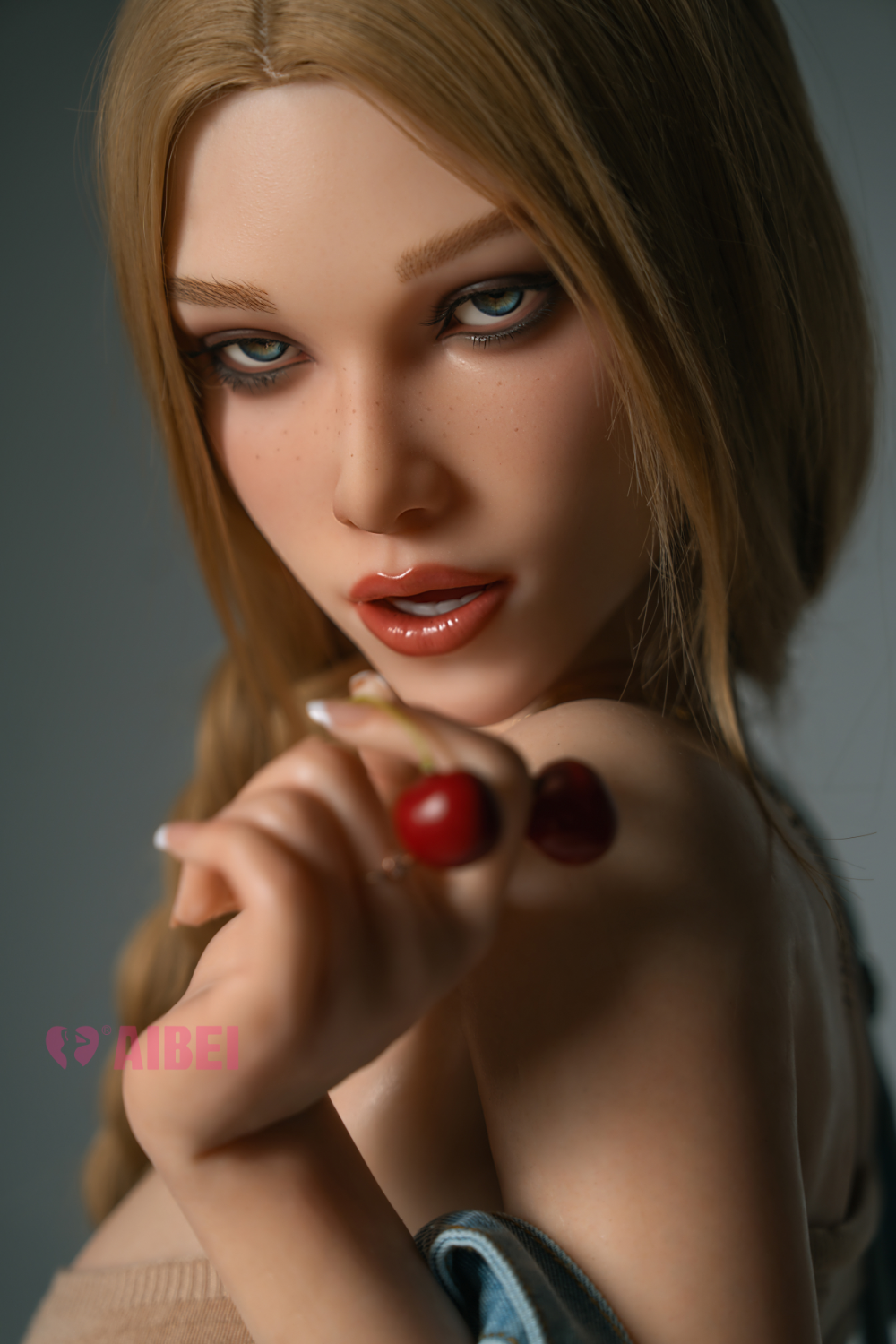 Close-up of Aibei Doll 158 cm F Silicone - Aria V3 with blonde hair wearing a beige knit top and holding a red cherry.