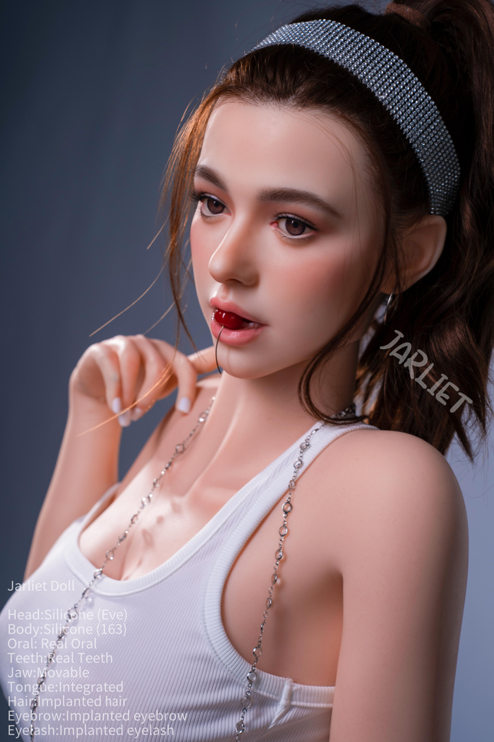 A side-profile portrait of the Jarliet Doll 163 cm D Silicone - Eve V2 looking off-camera. She has a cherry in her mouth, her hair is tied back with a silver beaded headband, and she is wearing a white tank top.
