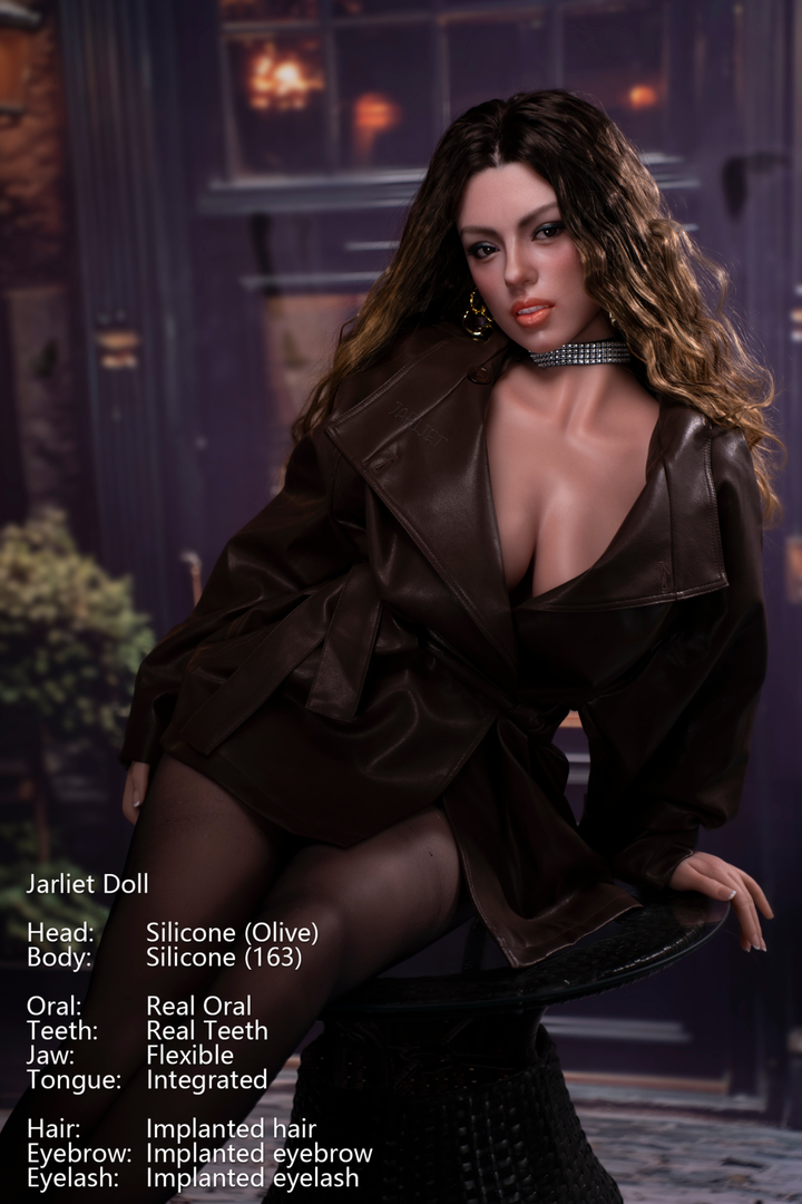 Jarliet Doll 163 cm D Silicone - Olive V2, seated in a brown leather jacket and black tights, wearing a silver necklace with a blue teardrop pendant.