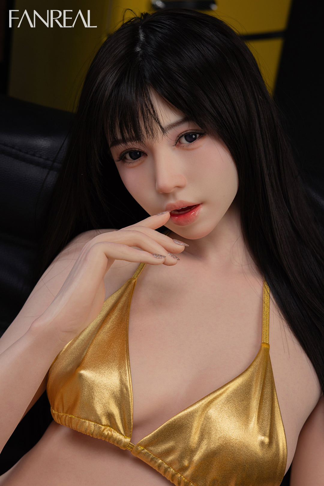 FANREAL Doll Nora V2 – 158cm B-Cup Realistic Silicone Sex Doll wearing a gold bikini top sitting in a black couch.