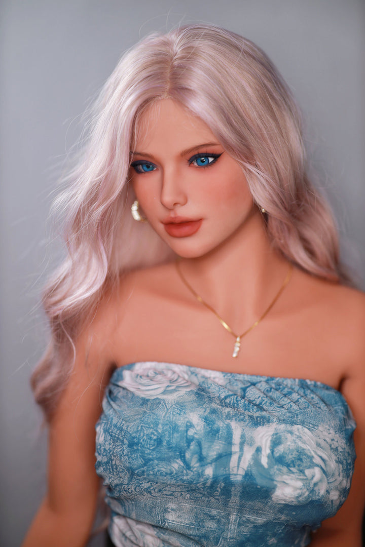 Fire Doll 166 cm C TPE - Flora three-quarter view in blue floral denim tube top and shorts, long pink-blonde wavy hair, bright indoor background
