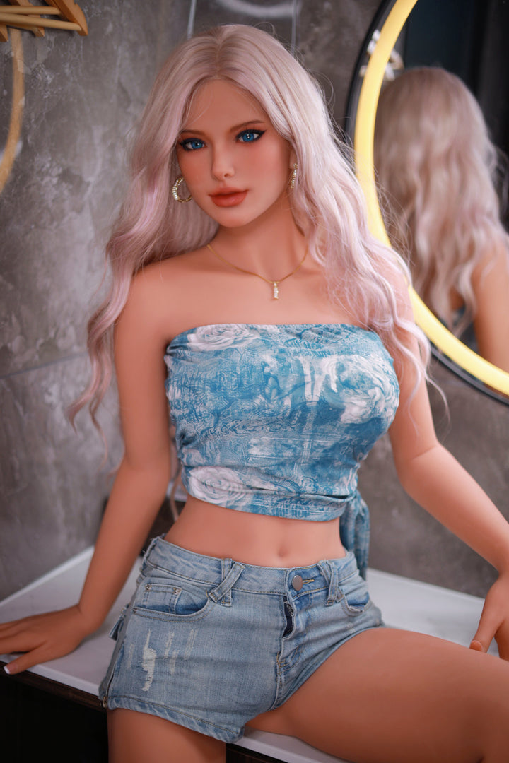 Fire Doll 166 cm C TPE - Flora full body side view in blue floral denim tube top and shorts, long pink-blonde wavy hair, bright indoor background
