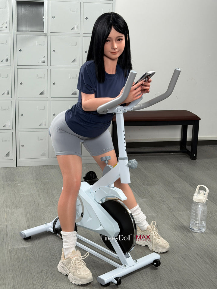 Firefly Diary Doll 153 cm B Max Series Silicone - Qiandao full body side view in navy blue t-shirt with exercise bike prop, short dark hair with bangs, gym indoor background