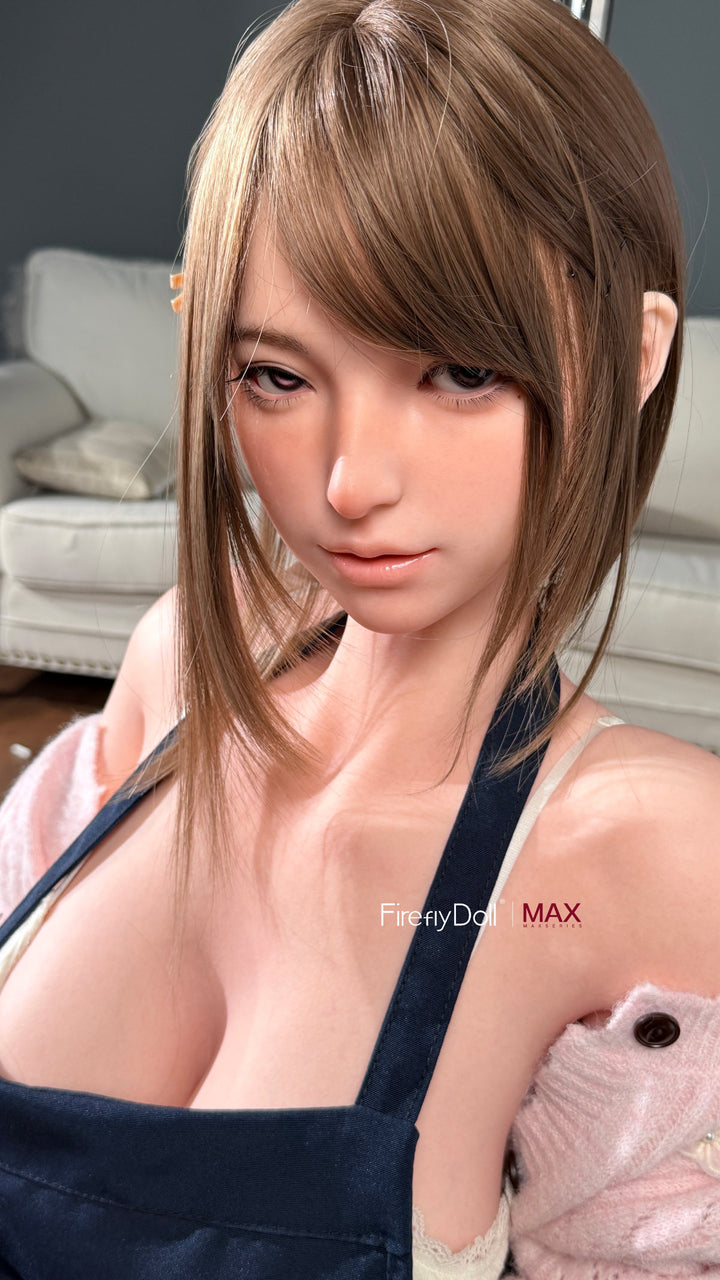 Firefly Diary Doll 164 CM I-Cup Max Series Silicone - Yuna close-up upper body view wearing navy blue apron with white cardigan, showcasing realistic facial features with light brown wavy hair against soft indoor background