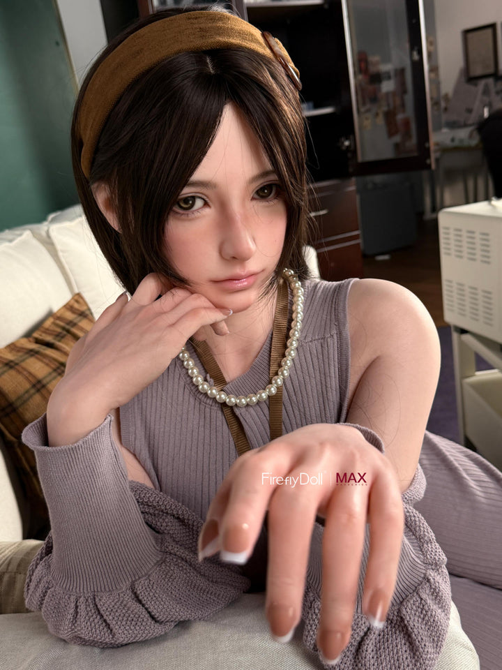 Firefly Diary Doll 165 cm B Max Series Silicone - Haruko V2 seated in a gray knit sweater dress on a cream couch, cozy interior setting