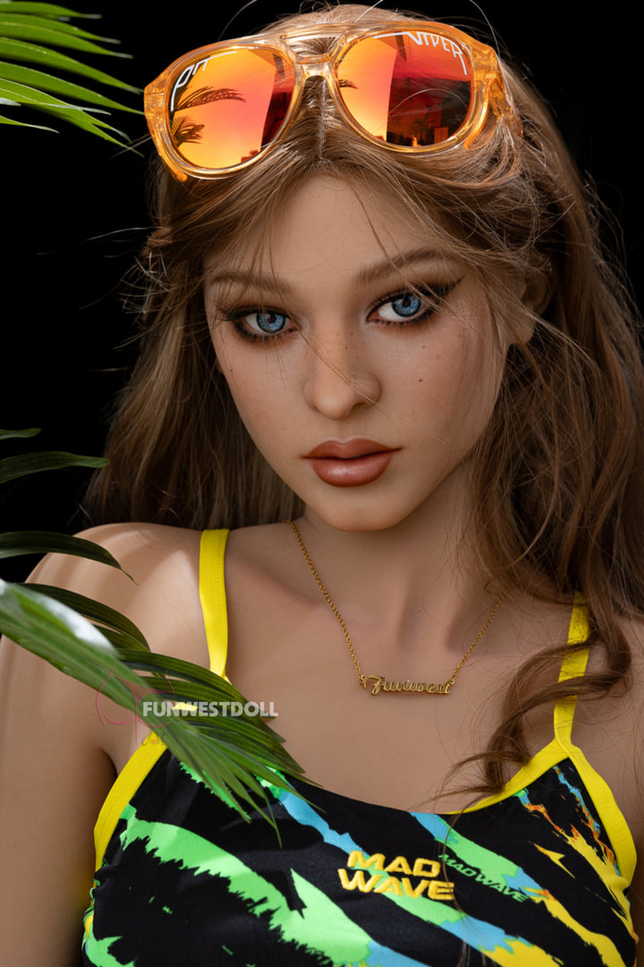 FunWest Doll 159cm F TPE - Sheila close-up portrait view wearing yellow green tropical print swimsuit with orange tinted sunglasses, showcasing realistic facial features with light brown hair against dark tropical foliage background
