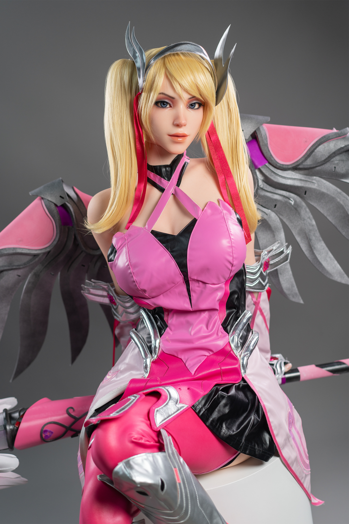 Game Lady 171 cm G Silicone - Mercy in pink and black outfit with wings sitting in a chair.
