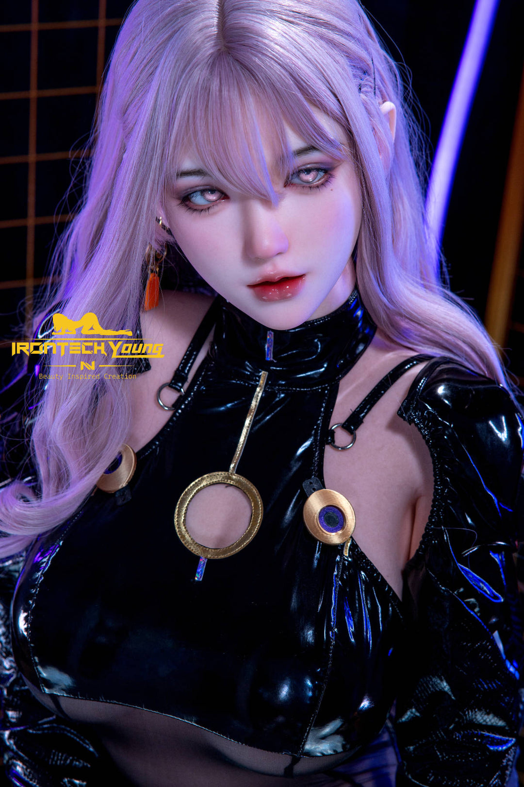 Irontech 165T E Young Series Silicone - Zia – long wavy lavender hair, pale grey eyes and a glossy black latex top with gold ring details, glowing neon lights behind her