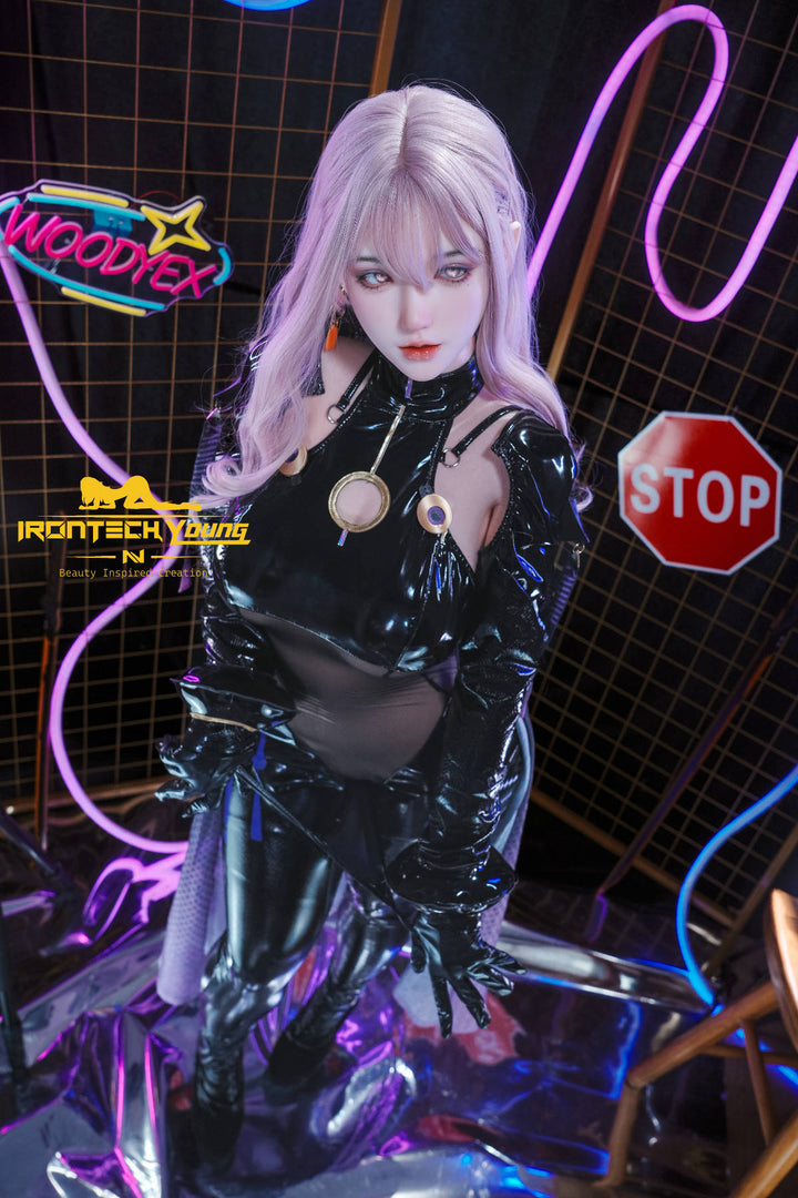 Irontech 165T E Young Series Silicone - Zia – seated in shiny black latex beside a red neon stop sign, lavender hair cascading over her shoulders