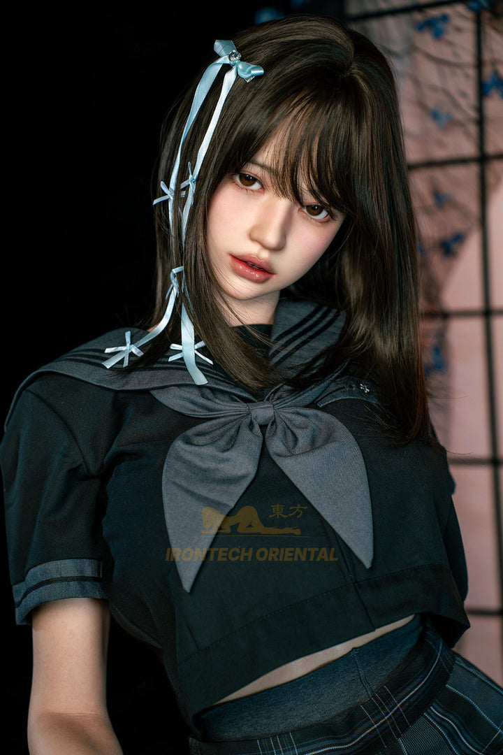 Irontech Doll 161cm F Oriental Series Silicone – Evie V4 – Close-up pose, black and grey kimono-style outfit with pale blue hair ribbons, dark hair styled with braided accents and bangs, traditional Japanese interior backdrop with shoji screen.