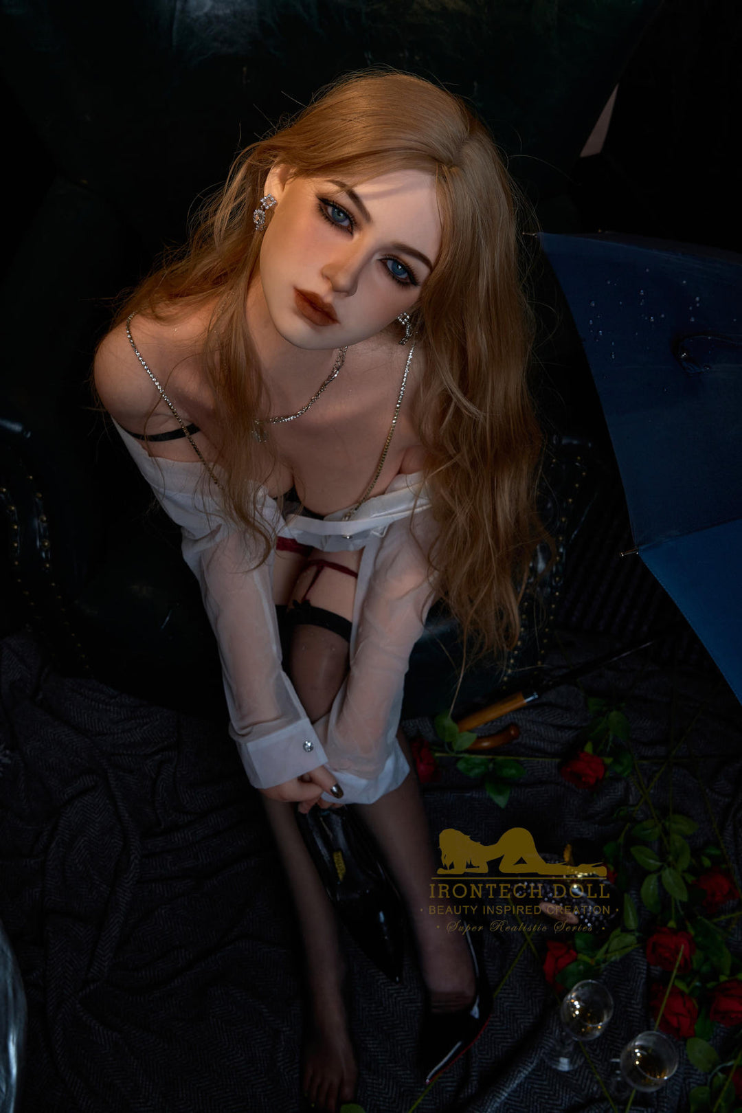 Irontech Doll 164 cm E Silicone - Flora  with blonde hair and a white outfit sitting in a chair.