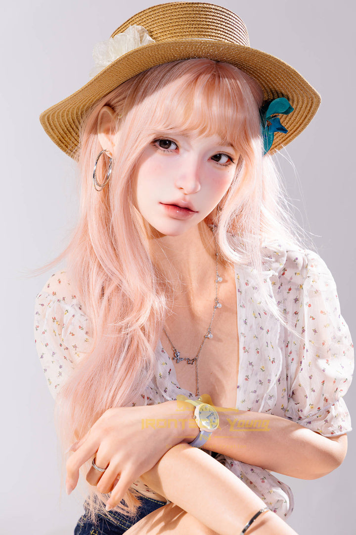 Irontech Doll 166 cm 2.0 Young Series E Silicone - Mio seated close-up holding a drink glass, straw sun hat, white top and denim shorts