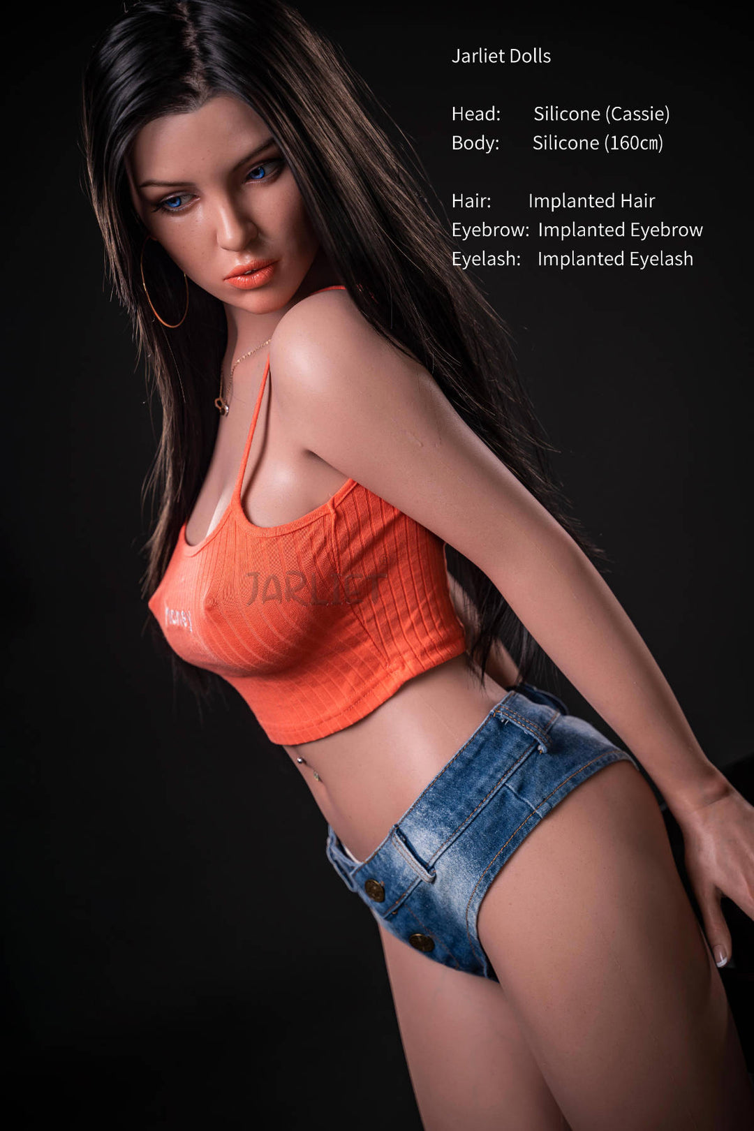 Jarliet Doll 160 cm C Silicone - Cassie standing pose in the orange top and denim shorts, gold hoop earrings, dark backdrop