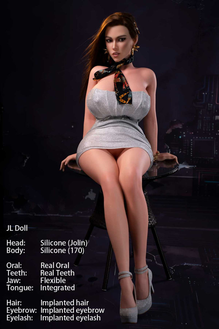 Jarliet Doll 170 cm G Silicone - Jolin wearing a sexy silver strapless mini dress and heels, seated front-facing pose on a glass table, dark blue background.