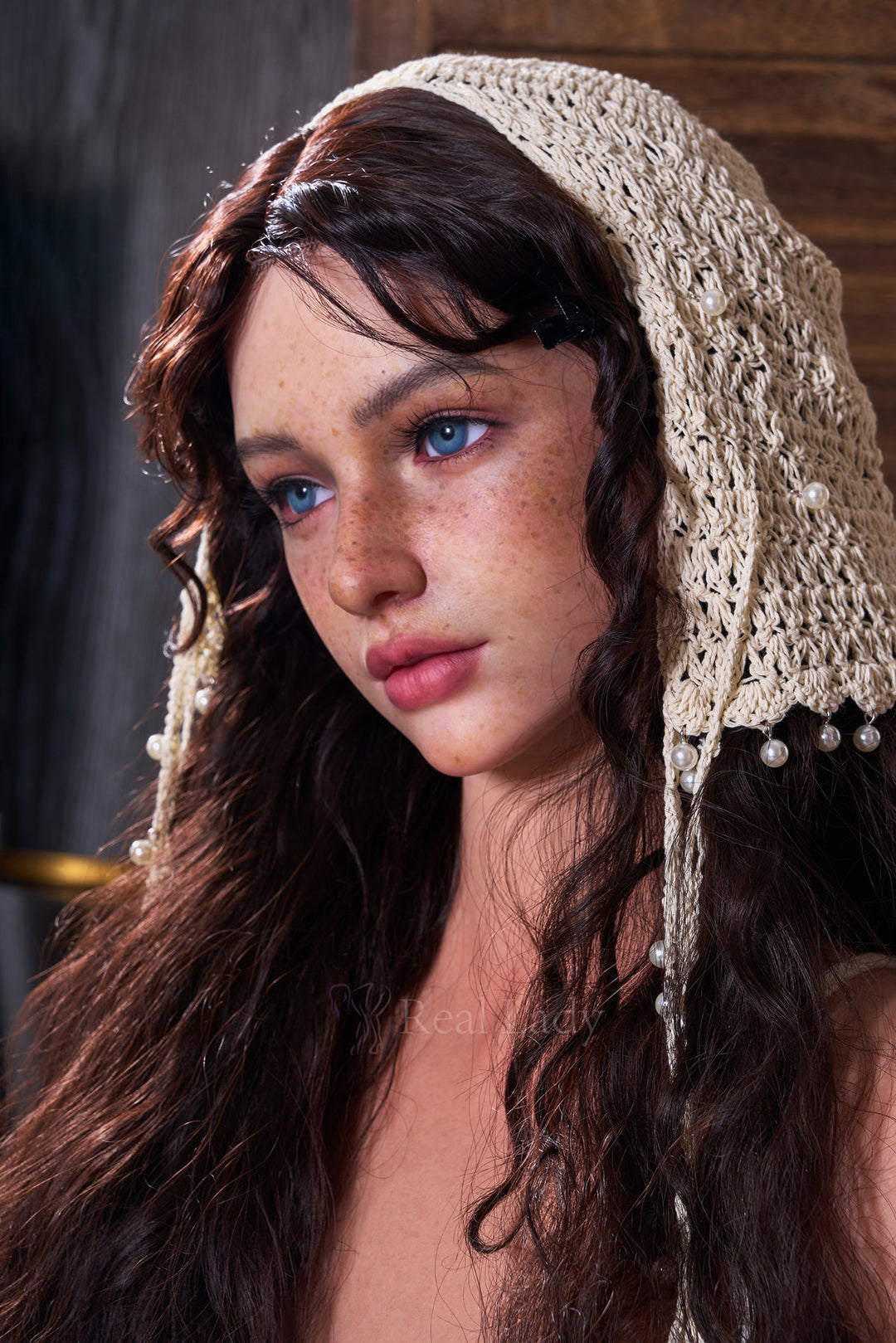 RealLady 159 CM H Silicone - Lena V4 close-up portrait view wearing white crochet headscarf, showcasing realistic facial features with long dark wavy hair and natural freckle details against warm rustic indoor background

