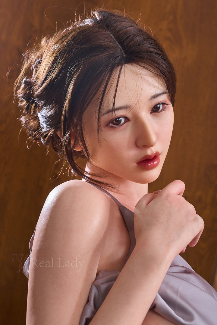 RealLady 159 cm H Silicone - Shizuka close-up upper body shot in grey satin slip dress with floral hair accessory, dark updo hair, warm wooden sauna background