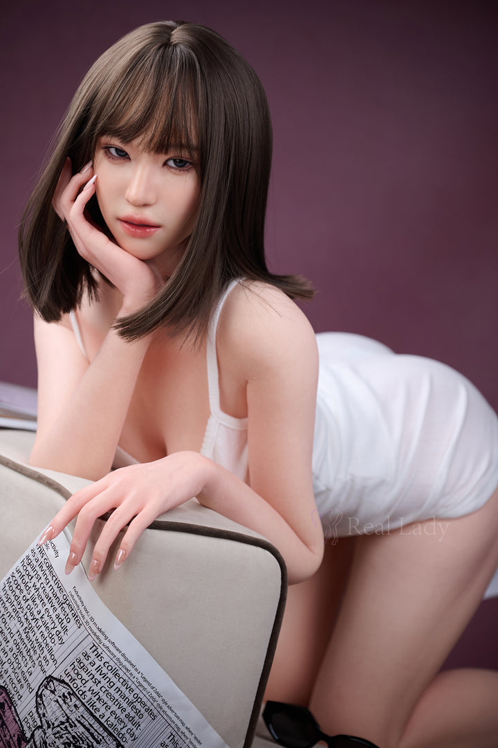 RealLady 150 cm E Pink Lover Series Silicone - Viki in a white tank top and shorts sitting on a couch with a newspaper.