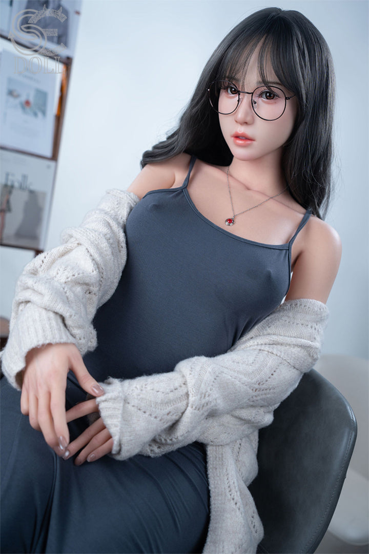 SEDOLL T160 cm C Aya Series Silicone -  Sena.A wearing a gray dress and white cardigan sitting on a chair.