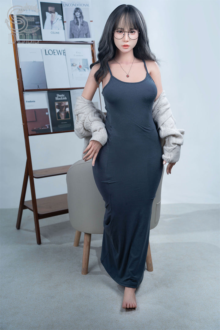 SEDOLL T160 cm C Aya Series Silicone -  Sena.A in a long dark dress standing in a room with a chair and shelves.