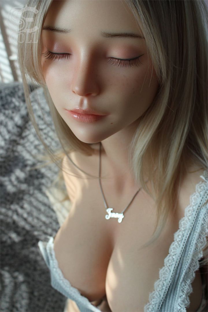 SEDOLL T161cm C Silicone Pro - Jenny.O – Close-up pose, light blue plaid top pulled down at the chest, wavy blonde hair framing the face, soft neutral backdrop.