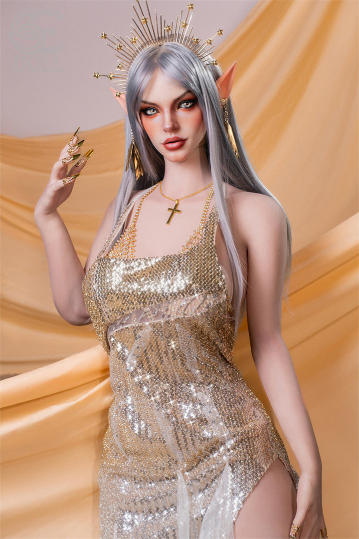 SEDOLL T167 cm E Silicone Pro - Evadora.A full-body pose in a shimmering gold sequined gown with a high thigh slit, silver spiked headpiece crowning her wavy silver hair, one hand raised near her face with rings visible, flowing gold silk drapery cascading behind her