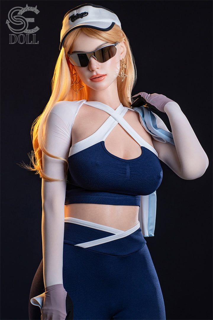 SEDOLL T175 cm E Silicone Pro - Nora.A standing side pose in sunglasses and navy harness top, helmet in hand