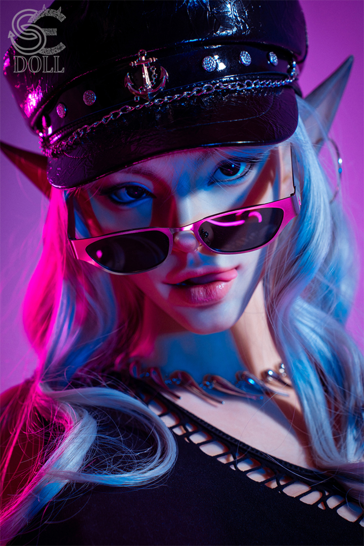 Close-up of SEDOLL T165 cm C Silicone Pro - Evadora.B with elf ears, blue hair, and a black captain’s hat under neon lights.