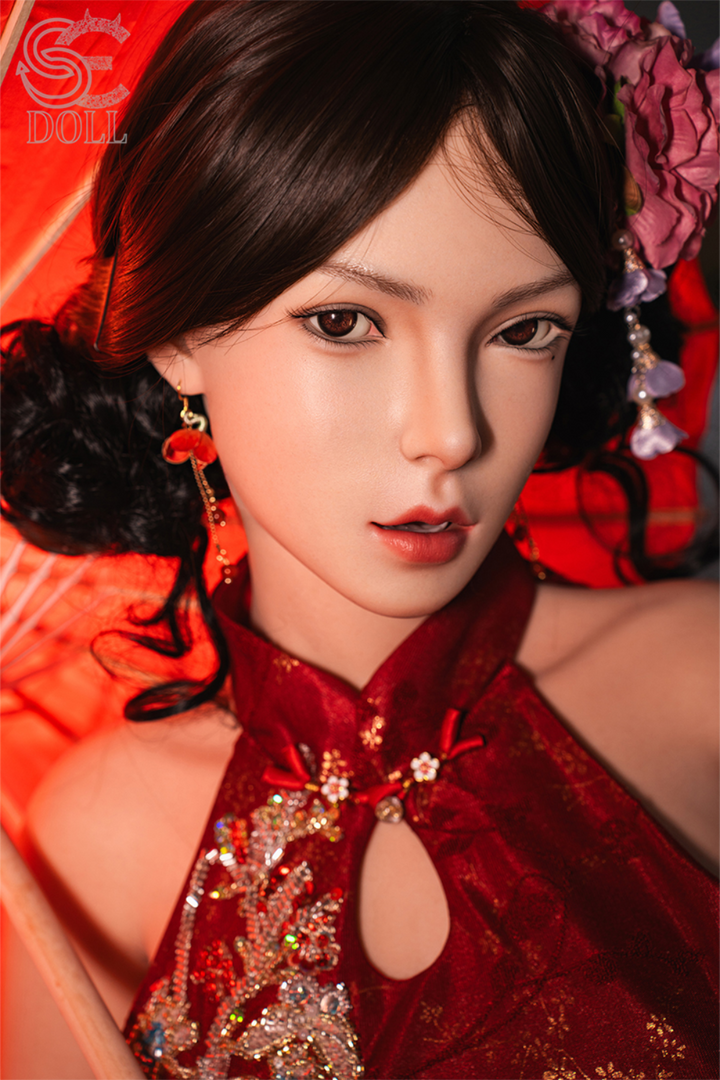 Close-up portrait of the SE DOLL T165 cm C Silicone Pro - Lumi.B, featuring a detailed face with dark eyes, dark hair styled with a flower, and a red sequined dress.