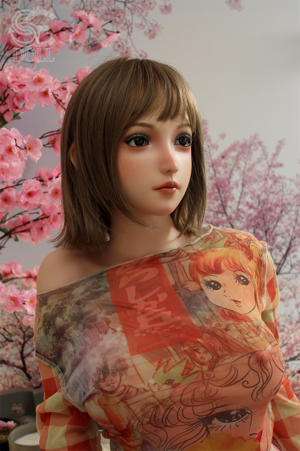 SEDOLL T160 cm B Silicone Pro - Yuuki.B looking off-camera, styled with short brown hair and wearing a colorful anime-print mesh top with pink cherry blossoms in the background.