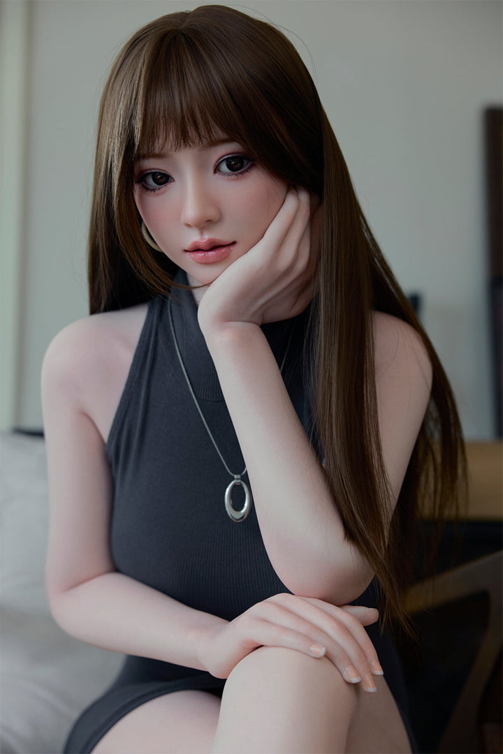 Starpery 171cm D - Snow – Seated pose, grey sleeveless top, necklace, brown bangs hairstyle, dark wood backdrop.