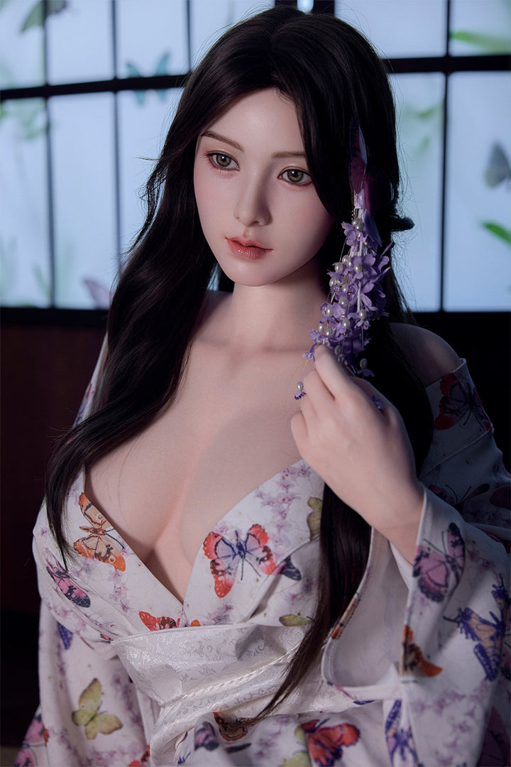 Starpery 171cm D - Xue V3 – Seated pose, floral kimono-style robe open at chest, purple flowers in dark wavy hair, dark backdrop.