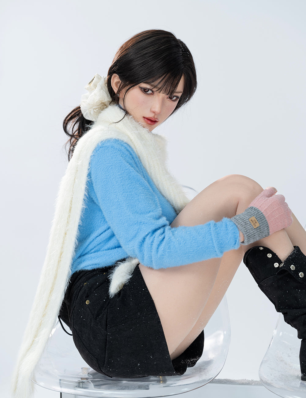 TOP-CYDOLL 168cm F-Cup Bingbing Realistic Sex Doll sitting on a clear chair wearing a blue sweater, black skirt, and black boots with white fur trim.