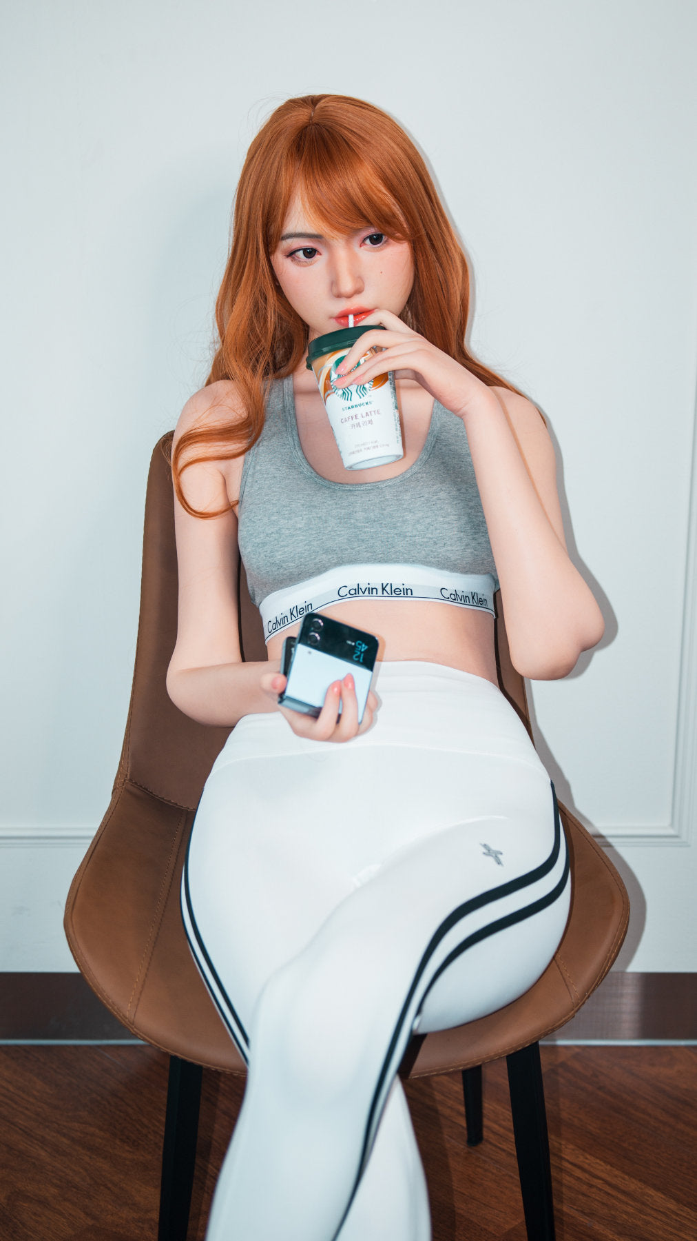 Zelex Doll K-Series 168 cm B Silicone - Suyeon three-quarter view in grey sports bra and white athletic leggings, long auburn hair, white studio background
