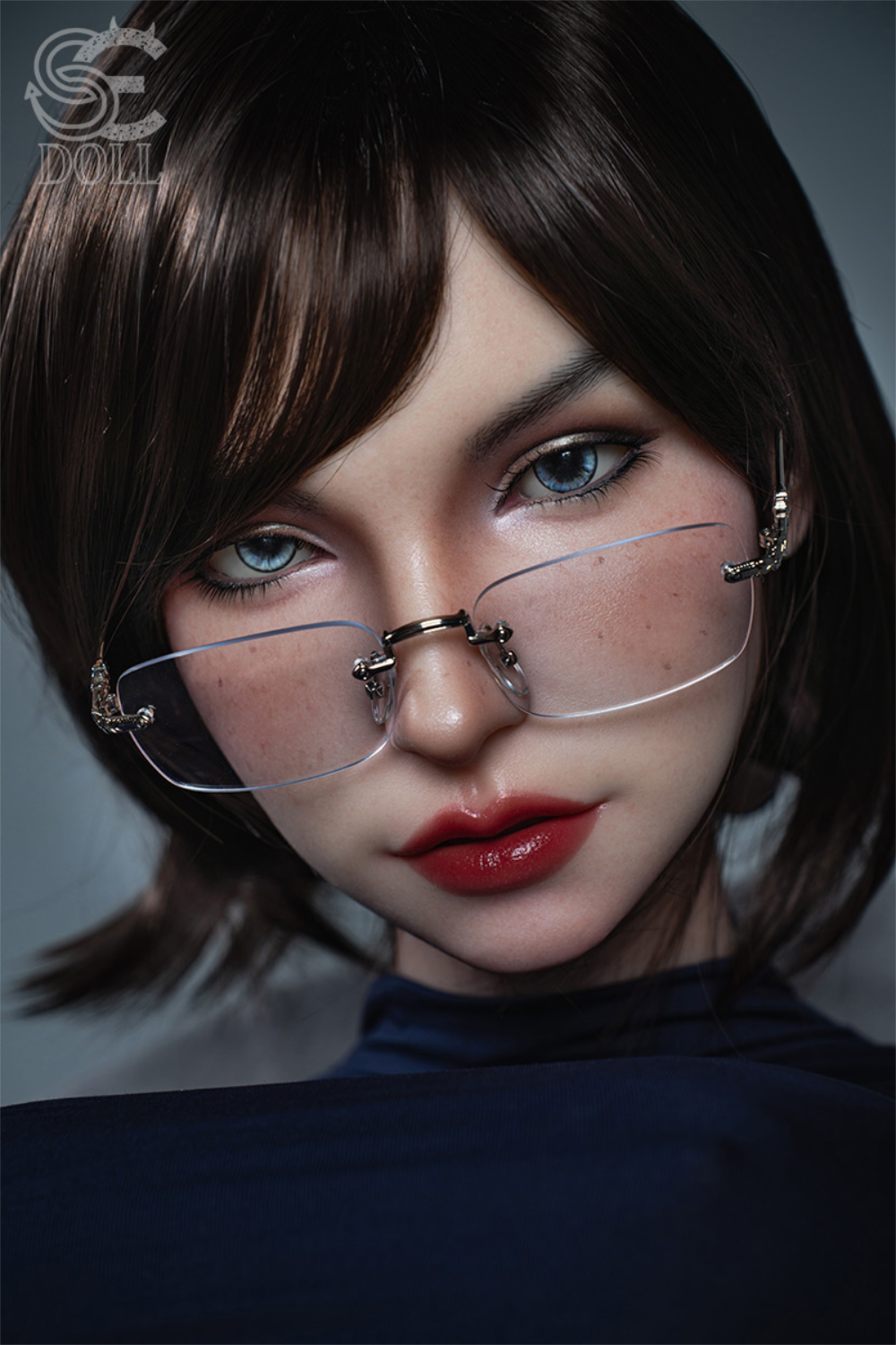 A high-detail facial close-up of the SEDOLL T114cm Zoe Ellis silicone head featuring light blue eyes, rimless glasses, and a short brunette bob.