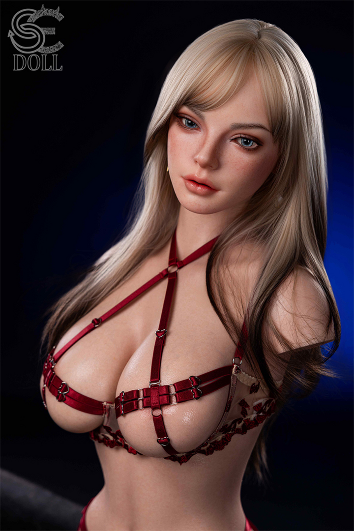 Frontal view of the Scarlett Reed silicone torso featuring blonde hair with dark lowlights, blue eyes, and red lingerie with heart-shaped hardware.